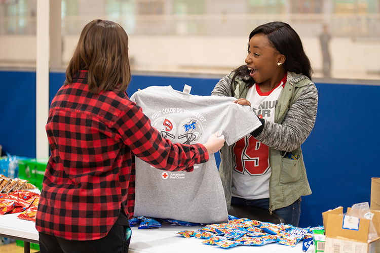 An MTSU student volunteer, right, shows off the 2019 "Blood Battle" T-shirt to a blood donor Monday, Nov. 18, during the university's annual "Bleed Blue, Beat WKU" blood drive competition with Western Kentucky University. 397 MTSU community donors helped the university win the friendly contest for the third straight year and the seventh time since 2010. (MTSU photo by James Cessna)
