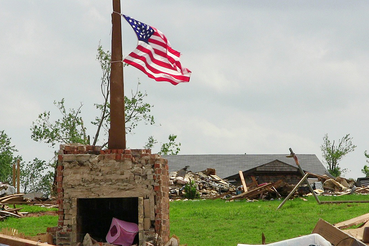 A U.S. flag stands in the rubble of a neighborhood struck by a deadly EF5 tornado that ravaged Moore, Oklahoma, and nearby areas May 20, 2013, killing 24 people and injuring 212 others. The tornado, which stayed on the ground for 37 minutes over a 17-mile path that crossed through a heavily populated area of the town, was part of a larger weather system that produced several other tornadoes across the Great Plains over the previous two days, including five that struck portions of Central Oklahoma the day before. (Photo by RevDP/Pixabay)