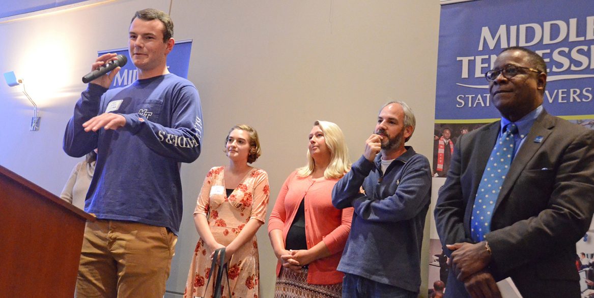 Aidan Orchard, left, a Daniel Boone High School senior, tells the audience at the MTSU True Blue Tour event Oct. 25 in Johnson City, Tenn., about his “awesome” experience when he toured the Murfreesboro campus recently. Listening at right is MTSU President Sidney A. McPhee. (MTSU photo by Randy Weiler)