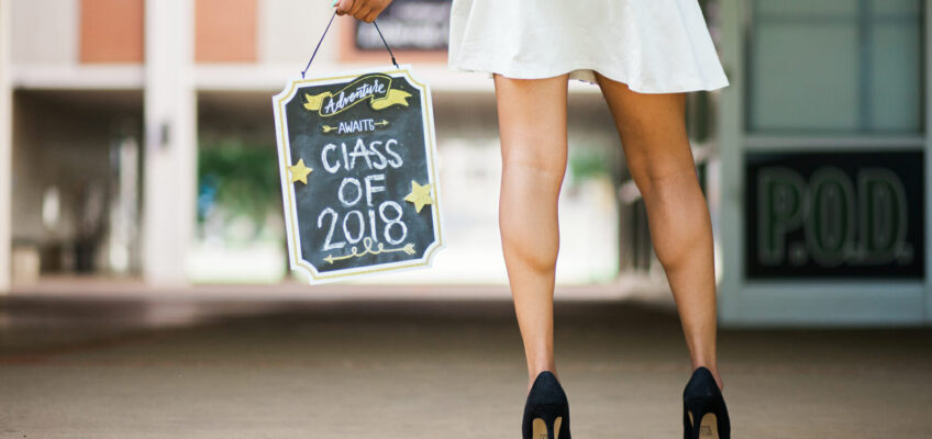 MTSU senior taking photos in Peck Hall with a "Class of 2018" sign. Photo by John Goodwin.