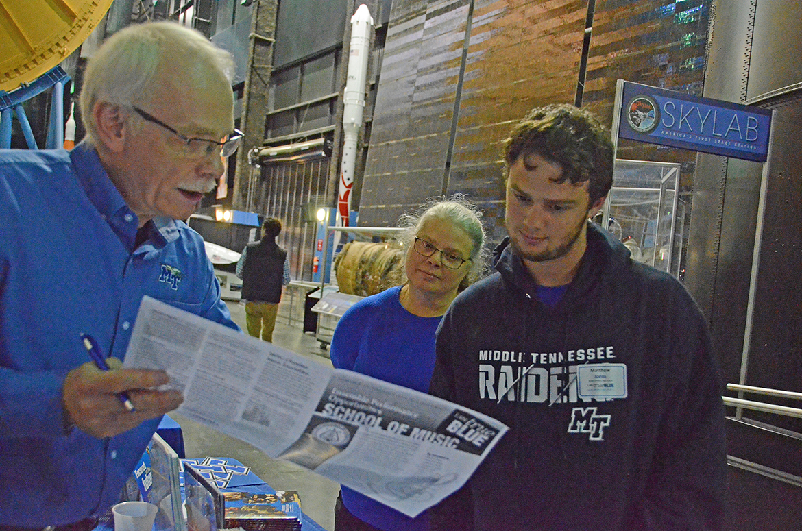 School of Music Director Mike Parkinson shows Casie and Matthew Joens information about the Band of Blue.