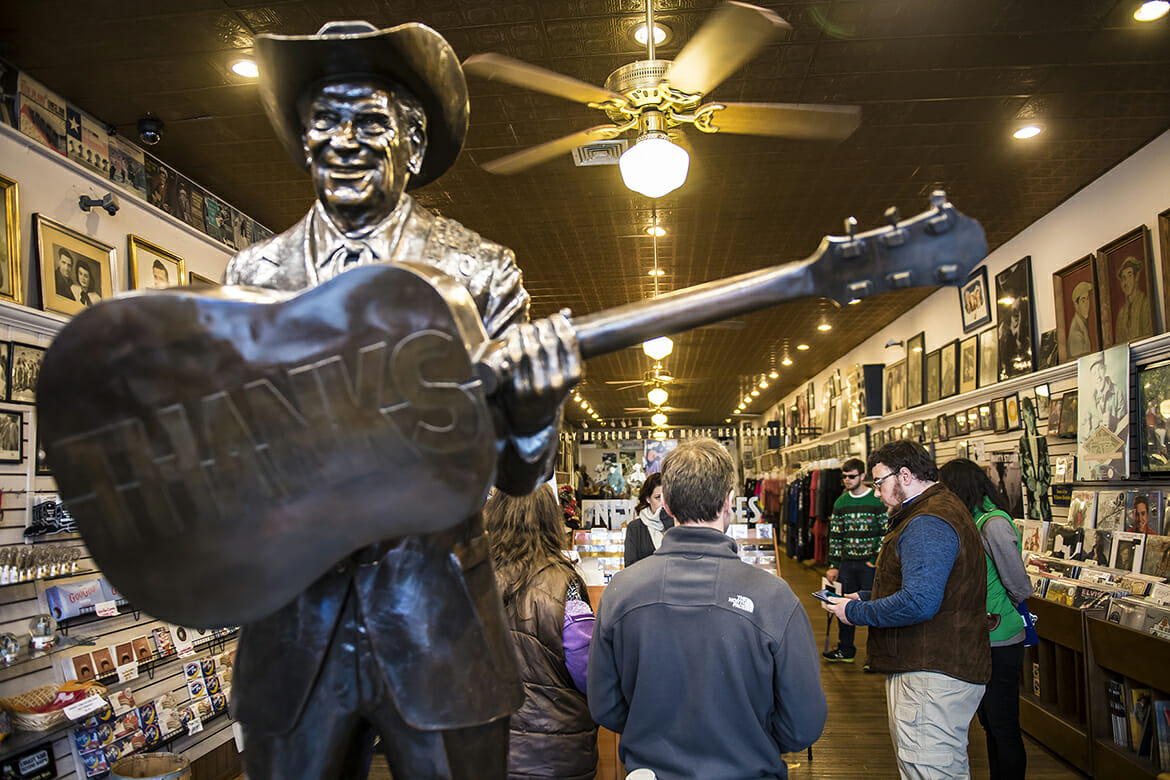 MTSU student Nathan Ledford, far right wearing a brown vest, shares his research from a digital tablet in the Ernest Tubb Record Shop at Broadway and Fourth Avenue. Ledford is a junior history major from Cleveland, Tennessee. (MTSU photo by Eric B. Sutton)
