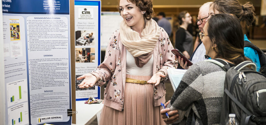 MTSU senior Maeve Bleistein, a then-psychology major from Franklin, Tenn., and 2018 MTSU graduate, discusses her poster and research with people attending the universitywide Scholars Day during the annual Scholars Week in 2018.