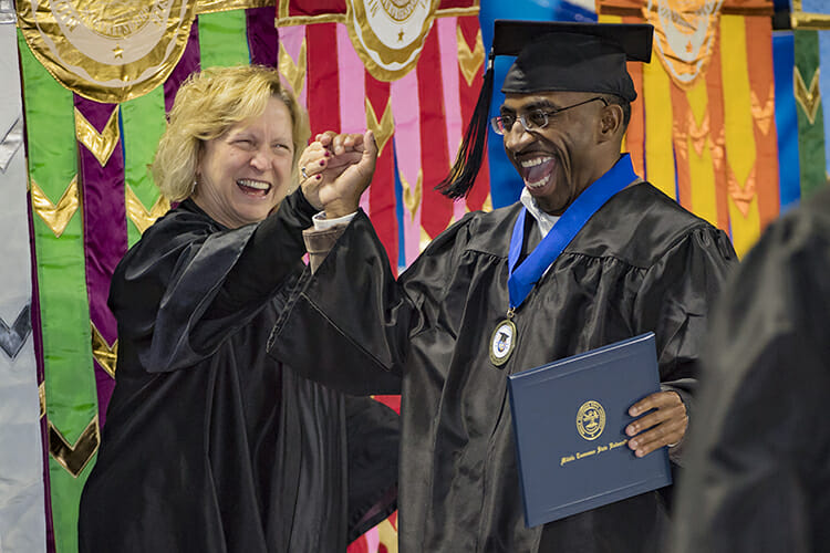 Joyful newly minted MTSU graduate Tyree Rumph, right, gets a congratulatory handshake from Pat Thomas, an assistant in the university president's office, after accepting his new Bachelor of Science in Liberal Studies degree at the fall 2017 commencement ceremonies in Murphy Center Dec. 16, 2017. Rumph's six-year academic journey to become a college graduate was aided by mentoring from MTSU Office of Accounting Services Director Ben Jones. (MTSU file photo by Kimi Conro)
