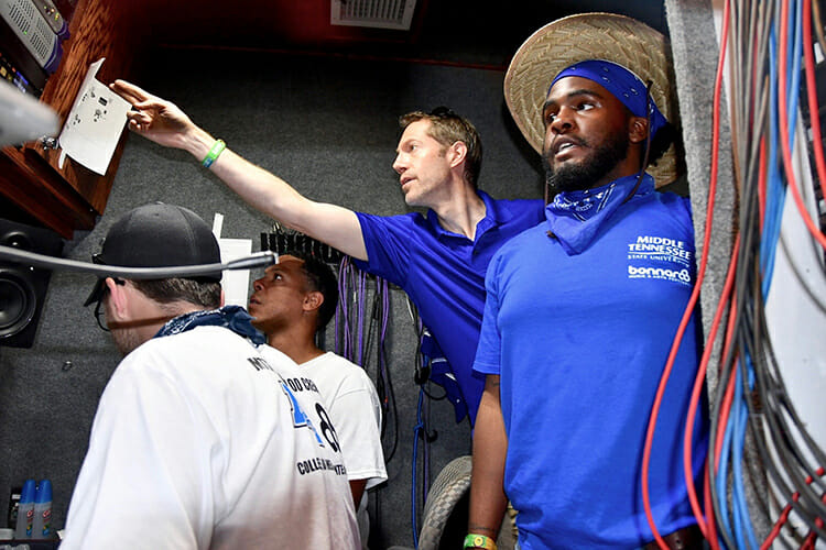 Michael Fleming, center, pointing, a professor in MTSU’s Department of Recording Industry who teaches audio engineering, helps Tevin RaShad Turner, right, a graduate student in recording arts and technologies, troubleshoot audio feeds before the first concert Saturday, June 9, on the Who Stage at the 2018 Bonnaroo Music and Arts Festival in Manchester, Tenn. Turner is the audio team leader for MTSU’s work at Bonnaroo this year. (MTSU photo by Andrew Oppmann)