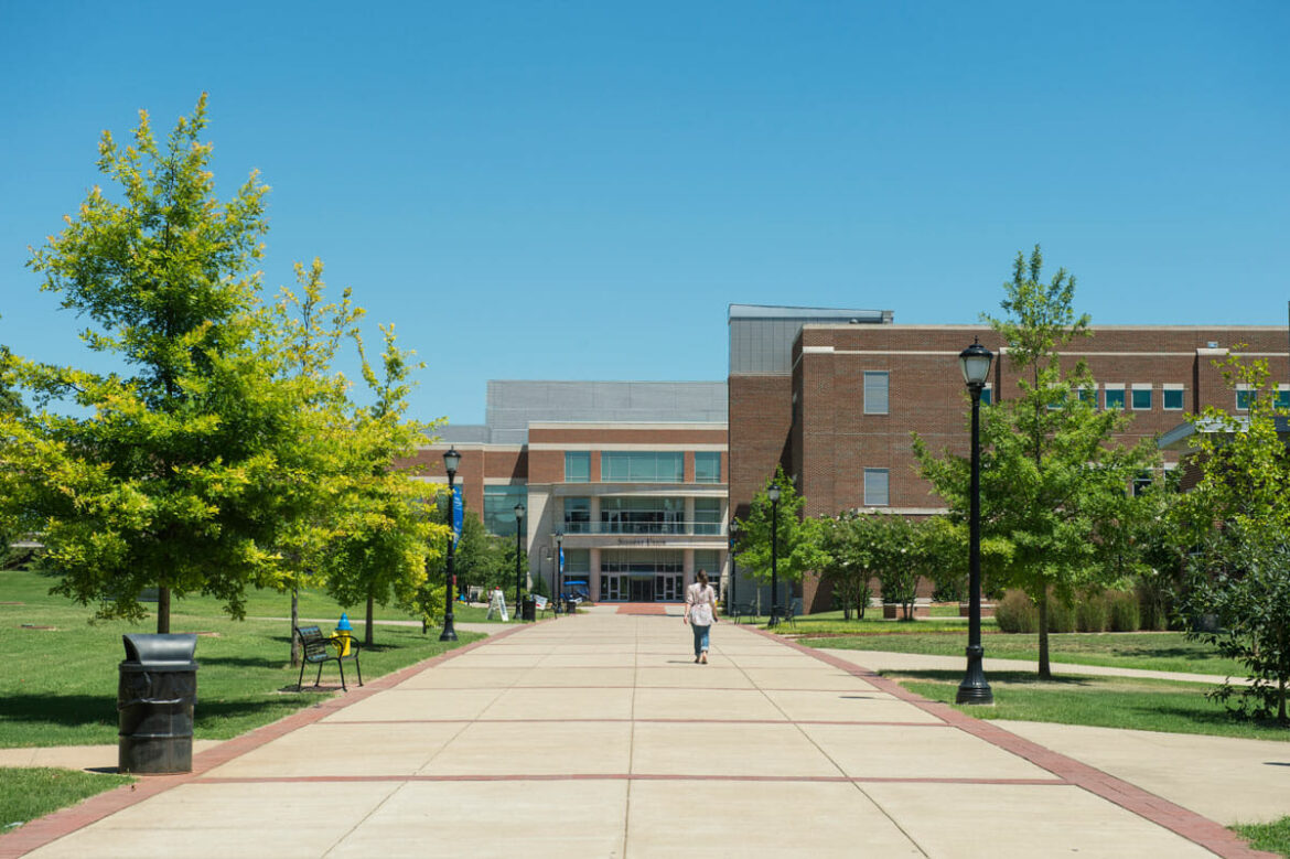 Student walking down sidewalk past the College of Education on the way to the Student Union building. Photo: Andy Heidt