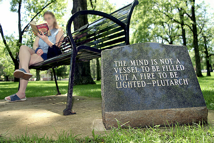 A visitor enjoys a little reading time on campus as she waits for her sister to finish summer orientation in this MTSU file photo. The marker next to her bench in MTSU’s historic Walnut Grove quotes the Greek historian Plutarch on the proper approach to education. (MTSU file photo by J.Intintoli)