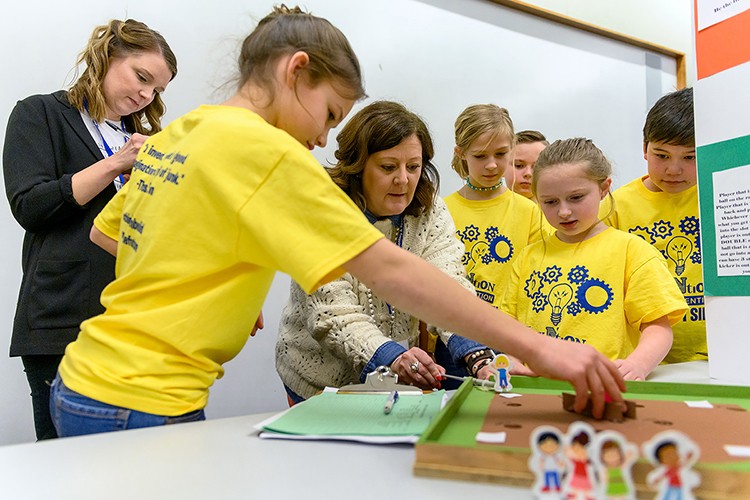 MTSU Invention Convention judges Katie Schrodt, left, a Department of Elementary and Special Education professor, and Middle Tennessee Christian School Principal Melanie Maxwell, center, play with the “Kickball King” board game invented by Erma Siegel Elementary fourth-graders Aurora Nelson-Keener, Lillian Bunney and Claire Couey as some of their classmates watch Feb. 21 in the Student Union Ballroom. Aurora, Lillian and Claire’s game won a ribbon as a “Judges’ Favorite” in the Fourth Grade Games category. (MTSU photo by J. Intintoli)