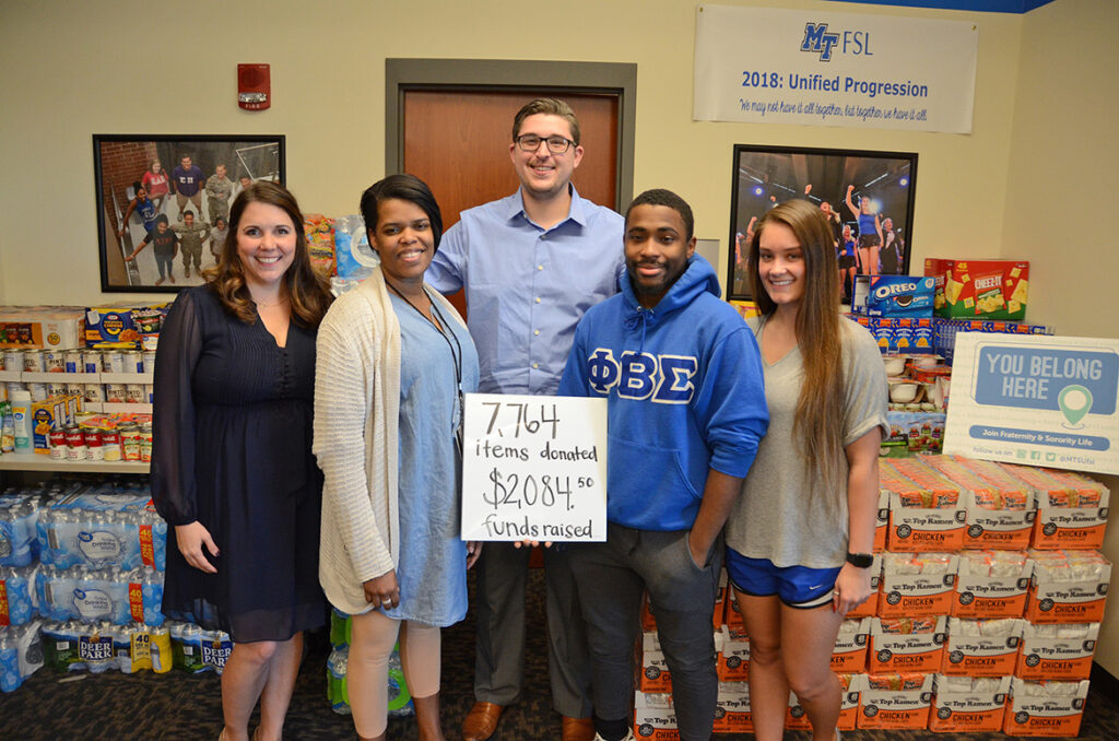 Representatives of the MTSU Greek Week committee, MTSU Fraternity and Sorority Life, and the Student Food Pantry stand in front of the thousands of donated nonperishable food items collected during the recent Greek Week food drive to replenish the pantry. Pictured, from left, outside FSL’s Student Union offices, are FSL Director Leslie Merritt; Danielle Rochelle, MT One Stop outreach coordinator who oversees the Student Food Pantry; Jordan Borchert, FSL coordinator; junior Deshaun Covington of Phi Beta Sigma fraternity and Greek Week committee member; and senior Alex Revor, member of Chi Omega sorority and Greek Week committee chair. As noted by the sign, the food drive collected 7,764 items and $2,084.50 in funds. (MTSU photo by Jimmy Hart)