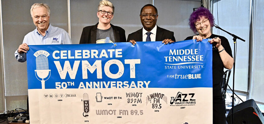 Ken Paulson, left, dean of MTSU’s College of Media and Entertainment, joins Val Hoeppner, executive director of WMOT Roots Radio 89.5, MTSU President Sidney A. McPhee and Jessie Scott, WMOT host, to display the 50th anniversary banner for the MTSU-owned station during a special celebration held Tuesday, April 9, at the Cyber Cafe on the Blue Raider campus. (MTSU photo by J. Intintoli)