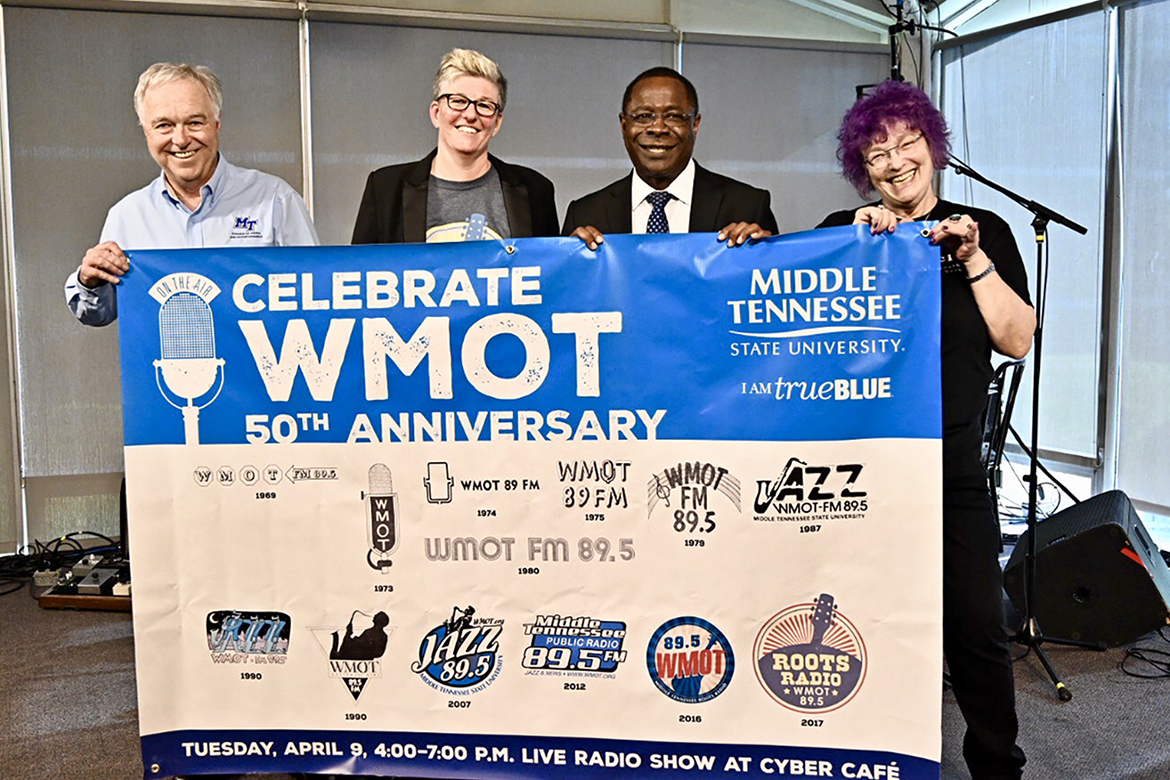 Ken Paulson, left, dean of MTSU’s College of Media and Entertainment, joins Val Hoeppner, executive director of WMOT Roots Radio 89.5, MTSU President Sidney A. McPhee and Jessie Scott, WMOT host, to display the 50th anniversary banner for the MTSU-owned station during a special celebration held Tuesday, April 9, at the Cyber Cafe on the Blue Raider campus. (MTSU photo by J. Intintoli)