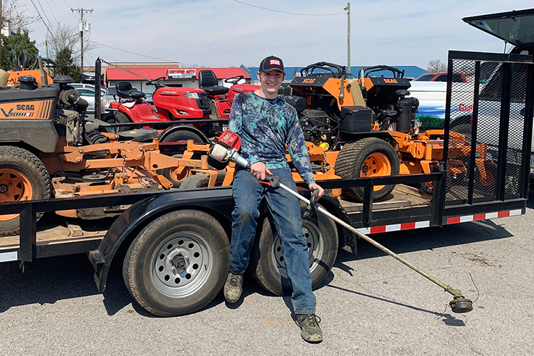 MTSU junior Nathan Fink of Horicon, Wisconsin, poses with the equipment he uses in his lawn-care business. Fink, a music business major and an entrepreneur since childhood, operates two businesses to pay for his college education and graduate debt-free. (Photo courtesy of Nathan Fink)