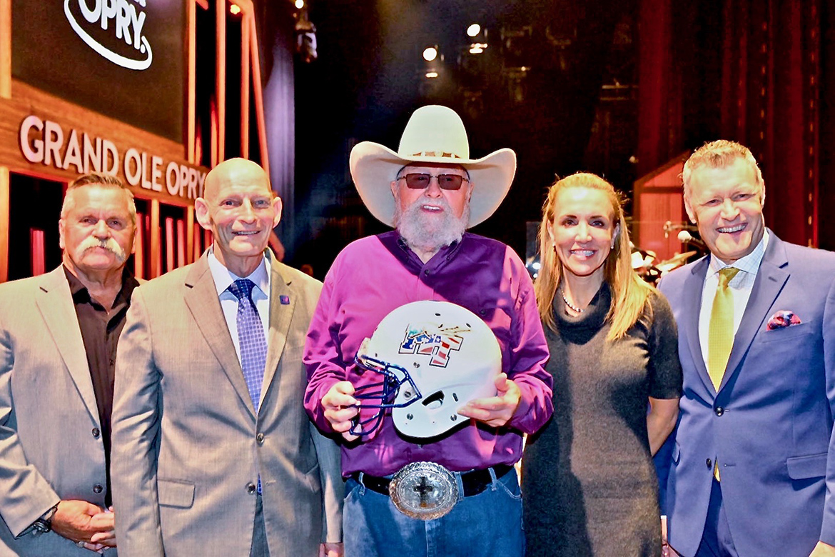 Charlie Daniels, center, shows off his new Blue Raider Football helmet given to him by MTSU’s Keith Huber, left of Daniels, and Hilary Miller, right of Daniels, after a surprise presentation at the Grand Ole Opry in Nashville, Tenn. In on the surprise was Daniels’ long-time manager David Corlew, far left, and Opry announce Bill Cody, far right. (MTSU photo by Cat Curtis Murphy)