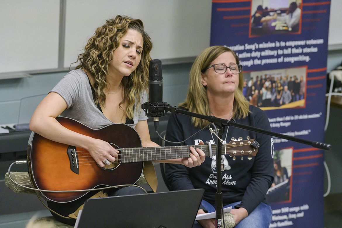Songwriter Jamie Floyd, left, plays and sings their new song while Jennifer Hyde of Murfreesboro, a U.S. Army mom and executive aide for the dean of MTSU's College of Education, listens at a special showcase for Operation Song's fourth annual “Songs and Stripes” event at MTSU Friday, Oct. 25. The event teams trios of military veterans, student and professional songwriters to create healing music for the veterans and training for the students. Not pictured is co-writer Abby Gibson, a senior commercial songwriting major from Roswell, Georgia. (MTSU photo by Andy Heidt)