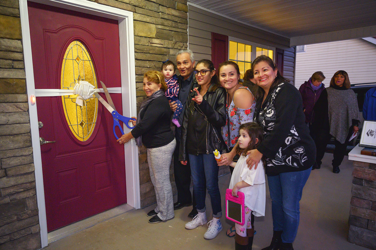 New Habitat for Humanity homeowner Rafela Aldas, left, cuts the ribbon for the new home she and husband Carlos Rivero-Odermatt will live in, as family members join them at the dedication Wednesday, Jan. 8, on East Castle Street in Murfreesboro. MTSU students helped with the build last fall. (MTSU photo by Cat Curtis Murphy)