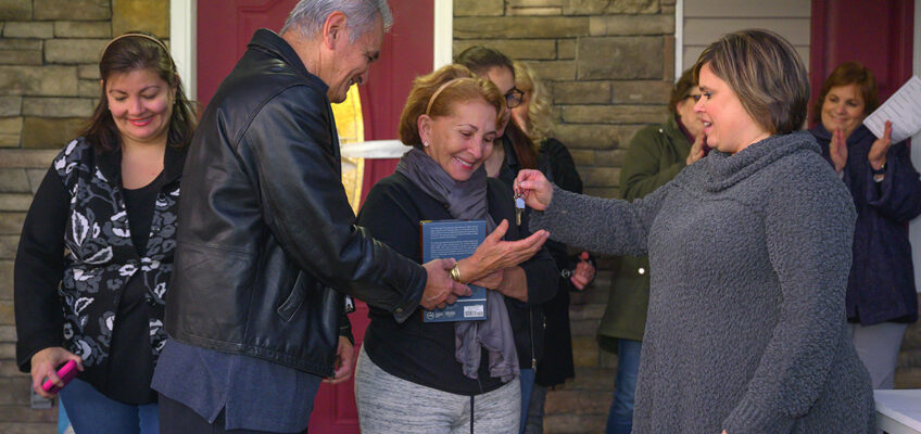 MTSU’s Jackie Victory, right, director of MTSU Student Organizations and Service, hands the keys to the new home for Carlos Rivero-Odermatt and Rafela Aldas Wednesday, Jan. 8, on East Castle Street, as their daughter, Annely Rivero Quinones, left, smiles with approval. MTSU students and other volunteers helped build the home. (MTSU photo by Cat Curtis Murphy)