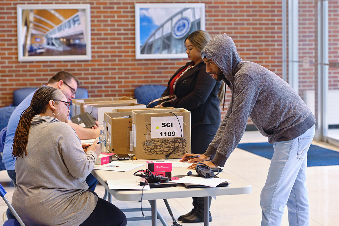 Yolonda Fields, front left, administrative secretary for MTSU’s Information Technology Division, helps a student with a laptop and internet hotspot checkout recently in the Cope Administration Building lobby. ITD has been lending a limited supply of such technology to students who need it since the university moved to remote courses for the rest of the spring semester. (MTSU photo by Cat Curtis Murphy)