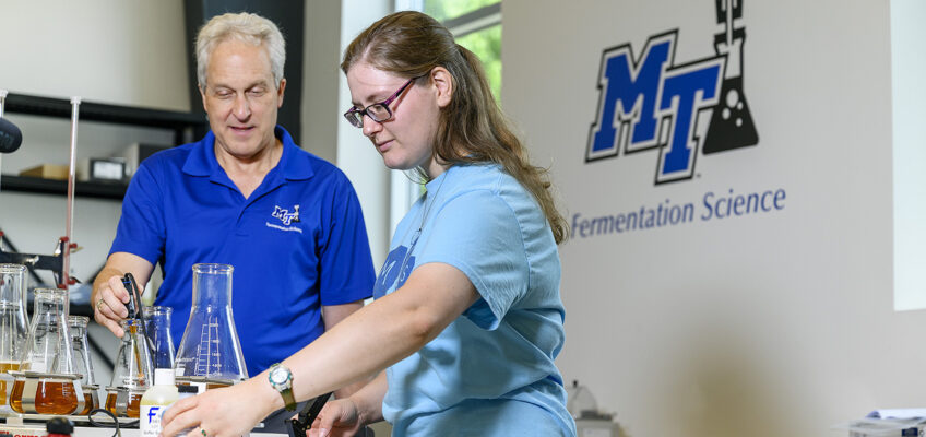 MTSU Fermentation Science Director Tony Johnston, left, oversees as former student and 2019 graduate Kayley Stallings works with ingredients and chemicals in the lab at university partner Hop Springs in Murfreesboro in this 2019 file photo. A three-year, $300,000 U.S. Department of Agriculture grant is an MTSU partnership with Motlow State and Columbia State community colleges, to help recruit students to agriculture and fermentation science. (MTSU file photo by J. Intintoli)