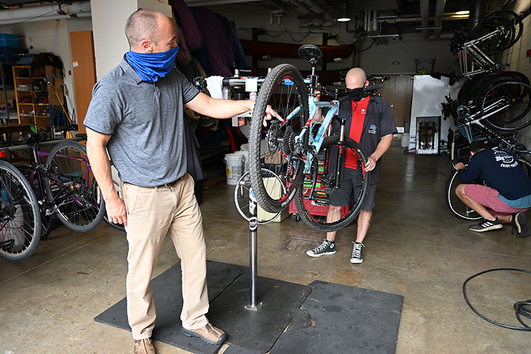 Josh Stone, left, associate director of recreation programming and bike shop supervisor working with Elden Winkelman, standing right, the shop’s head mechanic and a graduate student in international affairs. At far right kneeling is bike shop employee David Candeto. (MTSU photo by Stephanie Barrette)