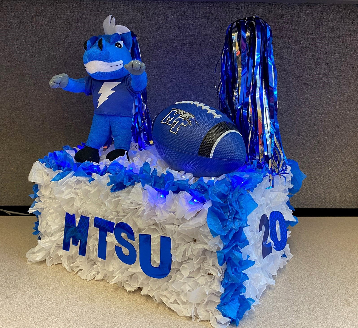 A stuffed animal version of MTSU mascot Lightning stands on a scaled-down version of a Homecoming Parade float with True Blue pom poms and MT football — one of about five dozen of entries submitted by Blue Raider faithful for the virtual “MTShUbox Parade” event broadcast Saturday, Oct. 3, from outside the Alumni House on Middle Tennessee Boulevard on True Blue TV. (Submitted photo)