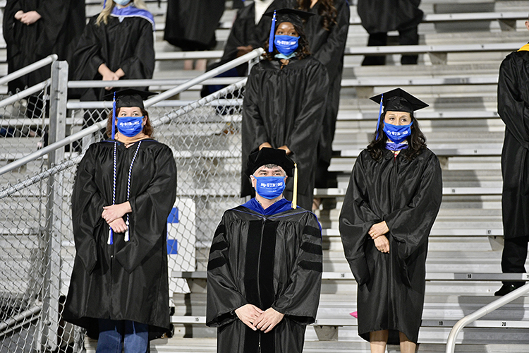 A group of MTSU students stand during a moment of silence at Floyd Stadium Saturday, Nov. 21, during the university's fall 2020 commencement ceremonies. MTSU, which held virtual graduations for its May and August graduates because of the pandemic, required strict mask, physical distancing and other health protocols for the graduates and limited their guests to help keep the three open-air events safer. (MTSU photo by Andy Heidt)