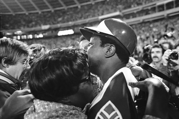 Hank Aaron, surrounded by reporters and photographers, hugs his mother, Estella Aaron, after hitting his 715th career home run in Atlanta-Fulton County Stadium on April 8, 1974, to break Babe Ruth's record. (Baseball History Comes Alive)