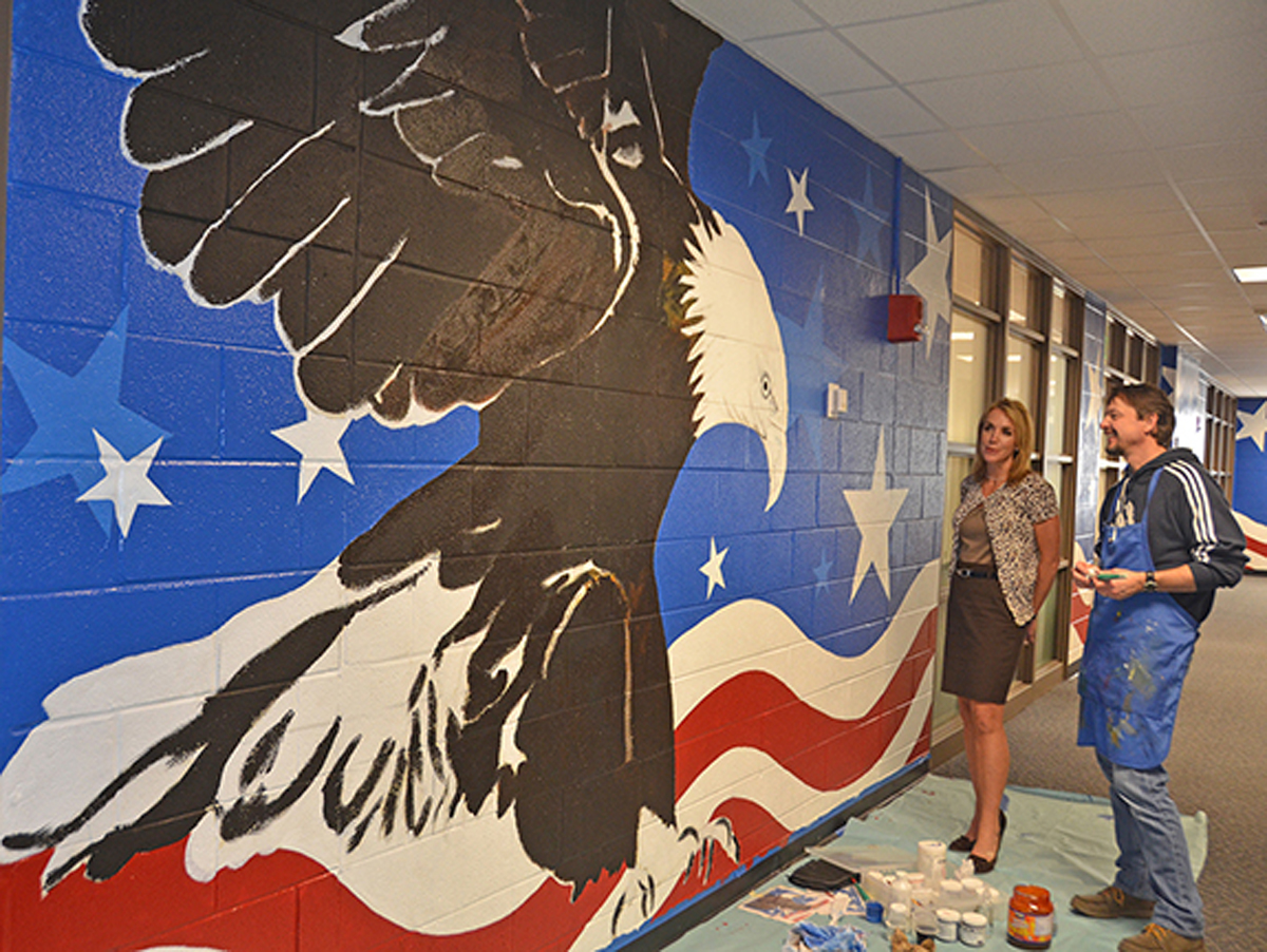 Hilary Miller, left, director of MTSU's Charlie and Hazel Daniels Veterans and Military Family Center, discusses the eagle mural with alumnus Randy Purcell, a professional artist, in the Keathley University Center. Purcell is painting a 70-foot section of the hallway outside the center. The center is home to 1,000 student veterans and family members who are welcome to participate in monthly virtual Roll Call veterans speaker events and more. (MTSU file photo by Randy Weiler)
