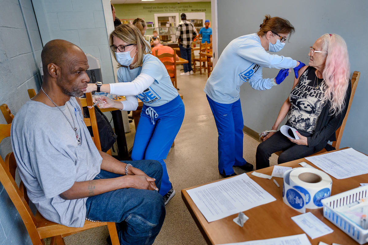 Greg Burrell, left, receives a one-shot Johnson & Johnson COVID 19 vaccine from MTSU Health Services registered nurse Tracy Mifflin and Teresa Ring, right, obtains her vaccine from MTSU RN Melissa Gray Friday, May 28, during a special vaccine clinic at Journey Home on West Castle Street. Journey Home Inc. is a Christian ministry that serves homeless people and the disadvantaged. (MTSU photo by J. Intintoli)