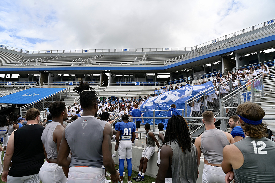 As Blue Raider football players look on, a group of MTSU students unfurl the giant Blue Zoo banner for the first time in two years on Thursday, Aug. 19, inside Floyd Stadium in preparation for the upcoming football season. (MTSU photo by Andy Heidt)