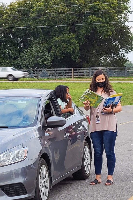 MTSU alumna Lydia Smith serves a family during the most recent drive-thru Literacy Night event at Walter Hill Elementary School. (MTSU photo by Stephanie Barrette)