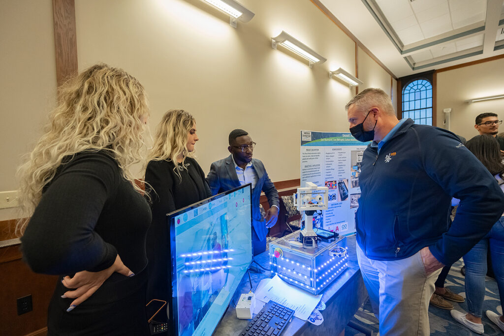 Competition judge Jeff Mech, right, listens as MTSU students Zani, left, and Lee Barnard and Jordan Pufon explain their project in the recent MTSU Engineering & Technology Mech-Tech Expo, held in the Ingram Building’s MT Center. The expo showcases students’ work during the fall 2021 semester. (MTSU photo by Cat Curtis Murphy)