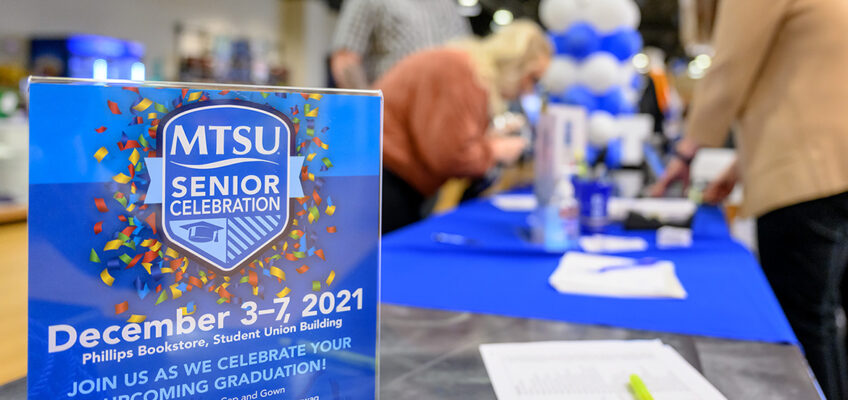 A flyer with information about MTSU's special four-day Senior Celebration sits on a table in Phillips Bookstore inside the Student Union Friday, Dec. 3, as members of the fall Class of 2021 pick up their academic regalia in the background. MTSU will hold its fall 2021 commencement ceremonies Saturday, Dec. 11, in Murphy Center. (MTSU photo by J. Intintoli)