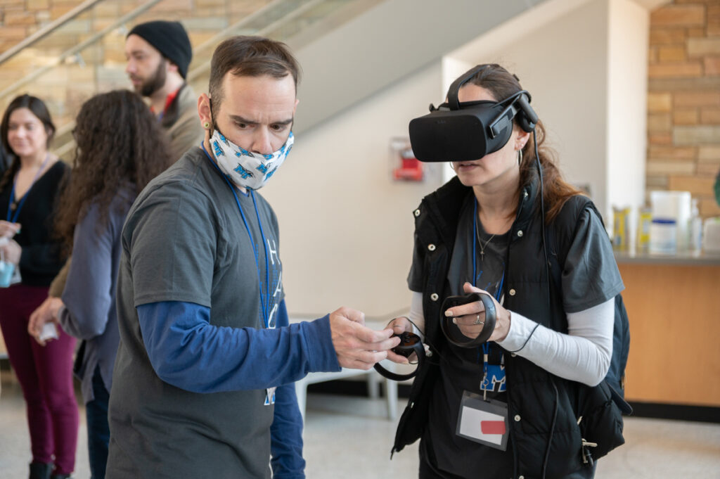 MTSU senior computer science major Brice Roberts, left, of Spring Hill, Tenn., assists Stephanie Moyer of Brentwood, Tenn., as she attempts to play the virtual reality escape game "Run Time Terror" during the seventh annual HackMT hack-a-thon Sunday, Jan. 30, in the MTSU Science Building's Liz and Creighton Rhea Atrium. Moyer is an administrative assistant with Antage, one of the event sponsors, and a professional studies major at the university though not currently enrolled in classes. (MTSU photo by James Cessna)
