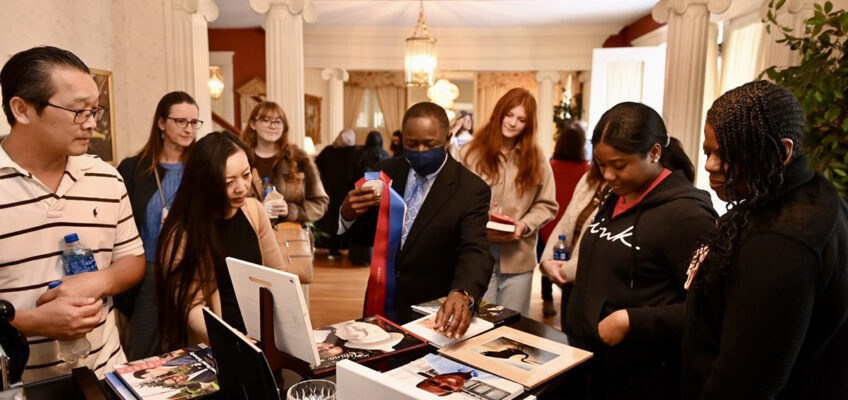 MTSU President Sidney A. McPhee, center, mingles with guests at his home, showing some of the photographs he has taken on past trips to China during the Presidents Day Open House Celebration of Scholars to conclude the visit by high school seniors who have been offered major scholarships by the university. Dozens of potential students and their parents accepted his offer to visit the house at the corner of East Main Street and Middle Tennessee Boulevard. (MTSU photo by James Cessna)