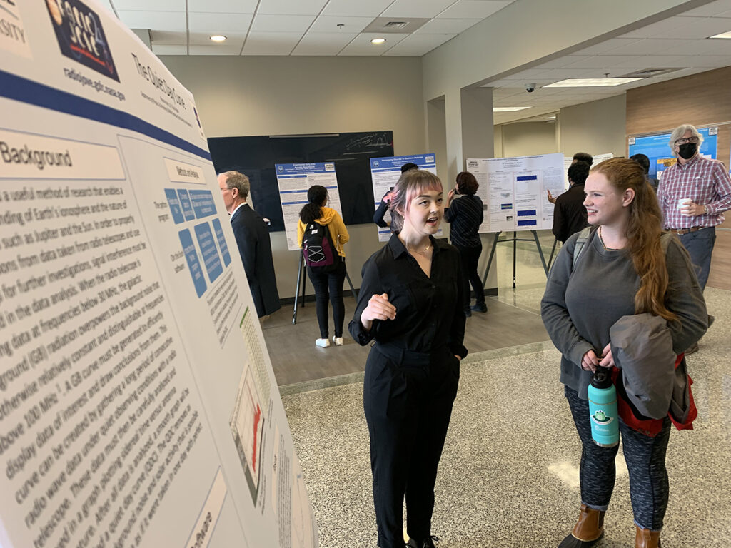MTSU junior physics major Phoenix Harris, left, of Franklin, Tenn., talks about her research experience with freshman Delana Howard of Murfreesboro March 17 during the first Department of Physics and Astronomy poster exhibit in Wiser-Patten Science Hall. Eleven students and seven faculty provided posters for the event. (MTSU photo by Randy Weiler)