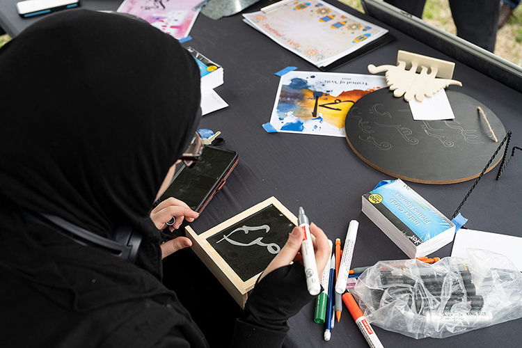 Fatimah Alnassari, an MTSU student, writes the name of a visitor to the Festival of Veils in the Arabic language. The booth was one of several on the Student Union Commons during the March 19 event. (MTSU photo by Cat Curtis Murphy)