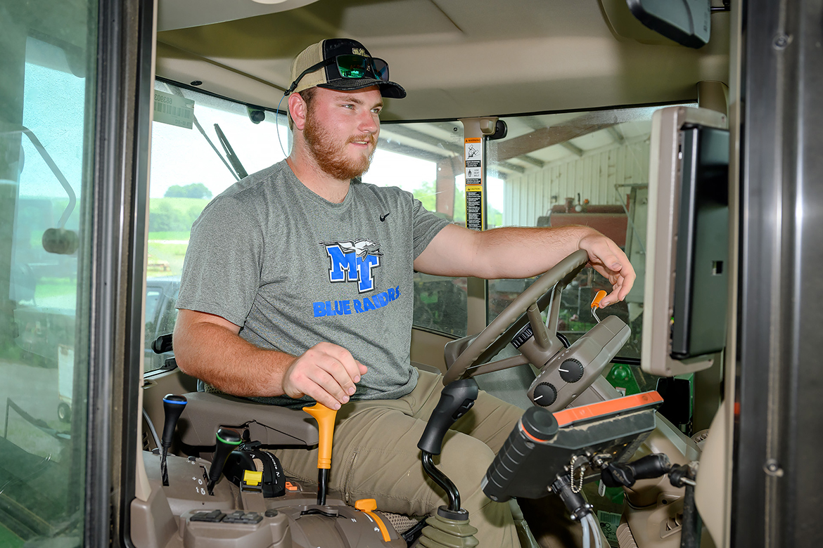 Wilson Kelly of Danville, Ky., drives a tractor at the MTSU Farm Laboratory in Lascassas, Tenn., about five miles east of campus. Kelly is a backup center on the MTSU Blue Raiders football team and an important part of the student worker team at the farm and dairy. (MTSU photo by J. Intintoli)