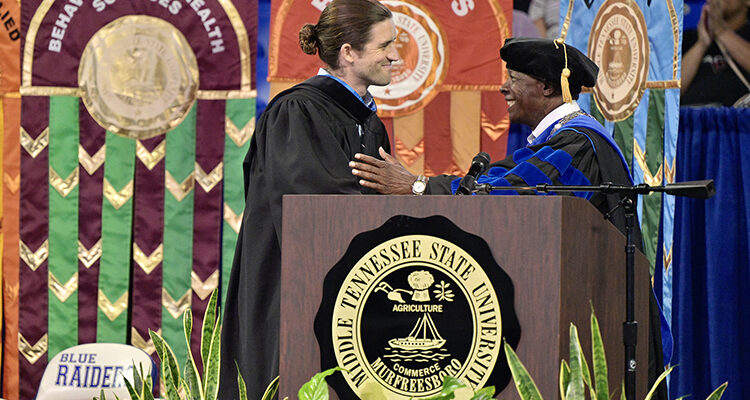 Andrew Forsthoefel, left, is welcomed to the platform by MTSU President Sidney A. McPhee Aug. 21 at the 2022 University Convocation at Murphy Center. Forsthoefel, author of "Walking to Listen," delivered the main address.