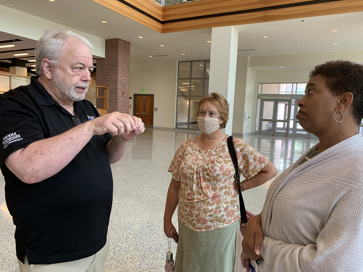 David Foster, left, MTSU Marketing and Communications director of marketing, shares information about a university benefit to take up to four classes a year with English Department instructor Patricia Gaitely and secretary Nicole Leonce recently in the Student Union first-floor atrium. (MTSU photo by Randy Weiler)
