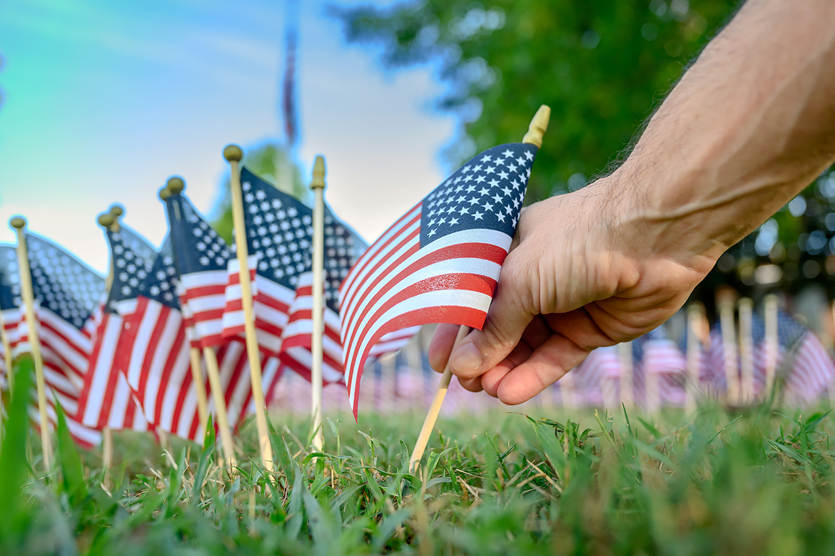 A volunteer places a small flag in the field of flags set up Friday, Sept. 9, for the upcoming 9/11 Remembrance event at the Tom H. Jackson Building's Veterans Memorial. The 2022 ceremony will begin at 7:30 a.m. Sunday, Sept. 11, marking the 21st anniversary of the terrorist attacks on U.S. soil. (MTSU photo by J. Intintoli)  