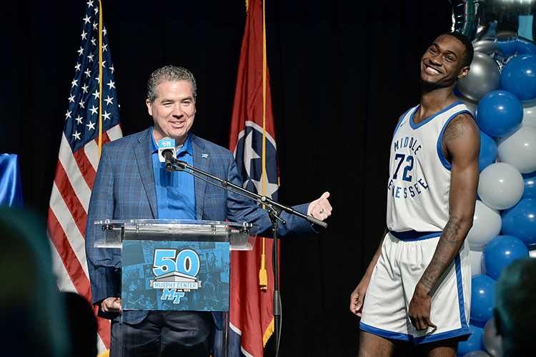 MTSU men’s basketball coach Nick McDevitt, left, jokes about the modeling skills of sophomore player and team captain Justin Bufford, who donned a retro uniform as part of a kickoff event Tuesday, Oct. 18, inside Murphy Center at Middle Tennessee State University for a yearlong celebration of the 50th anniversary of the iconic building. The uniforms will be worn during a special anniversary game Dec. 15 against the University of Tennessee-Chattanooga. (MTSU photo by Andy Heidt)