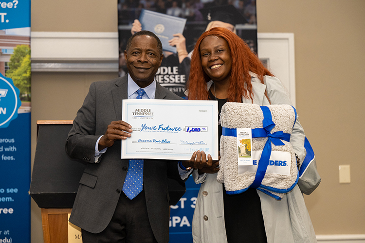 Prospective Middle Tennessee State University student and mom of five Shayanna Prinkey, right, smiles with University President Sidney A. McPhee after winning an MTSU-themed blanket and $1,000 scholarship at the True Blue Tour event on Wednesday, Oct. 5, 2022, at the Millennium Maxwell House in Nashville, Tenn. (MTSU photo by James Cessna)