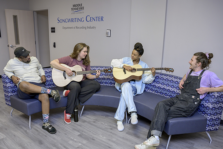 MTSU junior Eric Geter, left, of Powder Springs, Ga., and senior Brady Armstrong, right, of Edenton, N.C., both audio production majors, listen as junior music business major Marissa Powers of Louisville, Ky., and sophomore computer science and audio production major Michelle Greene of Nashville play a little music together between classes in the Department of Recording Industry's new Songwriting Center. The center, located five blocks east of campus at 508 E. Bell St., is holding classes now and plans a spring 2023 grand opening. The department's continuing growth and student success led Billboard to include it for the eighth consecutive time on the publication's newly released 2022 international list of top music business schools. (MTSU file photo by Andy Heidt)