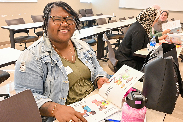 Shauntia Cook, Middle Tennessee State University graduate school counseling student and counselor at Oakland Middle School in Murfreesboro, Tenn., checks out the complimentary book she received as part of the MTSU College of Education’s annual Play Symposium event for early childhood educators and university students on campus on Oct. 1, 2022. (MTSU photo by Stephanie Wagner)
