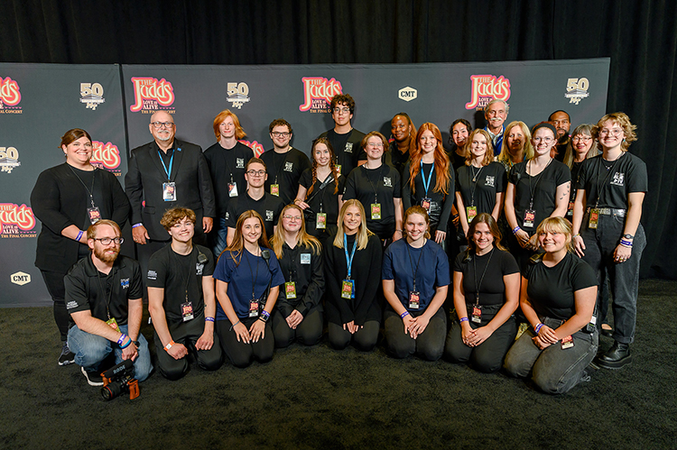 Middle Tennessee State University executive producer of True Blue TV Andrew Oppmann, second-from-left in the top row, stands with True Blue TV student-workers and staff for a photo on the stage of “The Judds: Love is Alive – The Final Concert” event, which they helped work on the broadcast and production of, on Thursday, Nov. 3, 2022, at the Murphy Center on campus. (MTSU photo by James Cessna and Cat Curtis Murphy)