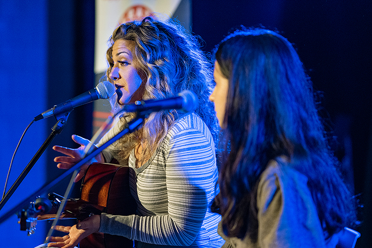 Grammy-nominated songwriter Jamie Floyd, left, explains how she and MTSU student Emily O'Neal, right, a native of Starke, Florida, and senior commercial songwriting major who now lives in Murfreesboro, co-wrote a new song, “Something I Love More," with student veteran Karly Stevens of Cumberland Furnace, Tennessee, during the annual Operation Song writers' retreat at the university. Stevens, a freshman horse science major who served in the U.S. Navy, was unable to join her new colleagues and six other writing trios to perform their songs in MTSU's Keathley University Center Theater at the Oct. 28 event. MTSU's Charlie and Hazel Daniels Veterans and Military Family Center and the Commercial Songwriting Program have hosted Operation Song since 2016. (MTSU photo by Cat Curtis Murphy)