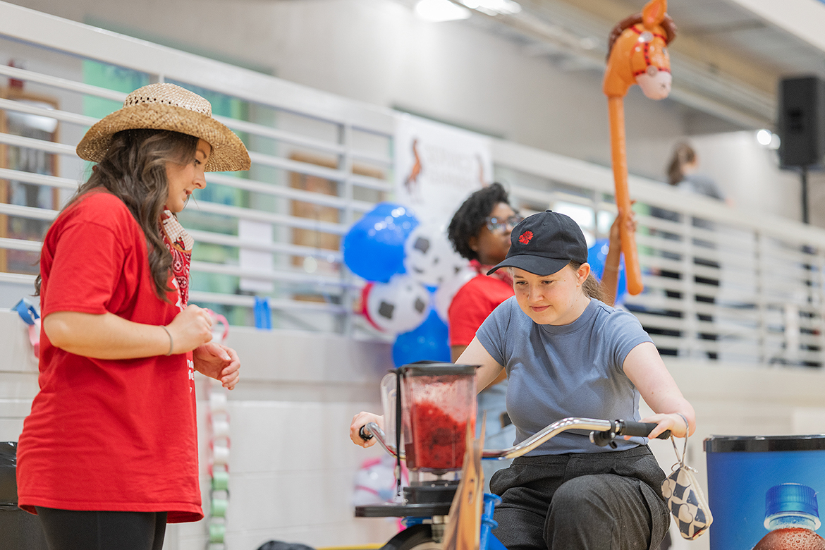 Natalie Williams, left, a Middle Tennessee State University student in a service learning project for a health promotions class, watches as an MTSU Relay for Life participant makes a smoothie while riding a stationary bicycle during the event held March 22 in the Campus Recreation Center in Murfreesboro, Tenn. MT Dining provided the bike and supplies to make the smoothies. (MTSU photo by Cat Curtis Murphy)
