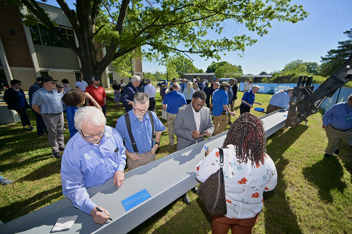 Retired Middle Tennessee State University professor Ron McBride, left, signs the final steel beam to be placed atop the new Applied Engineering Building Wednesday, May 1, as Engineering Technology lab director Rick Taylor and Tony Lee, MTSU alumnus and Nissan lead quality engineer, wait their turn. The facility, which will be adjacent to the School of Concrete and Construction Management Building, is expected to open by the start of the fall 2025 semester. (MTSU photo by J. Intintoli)