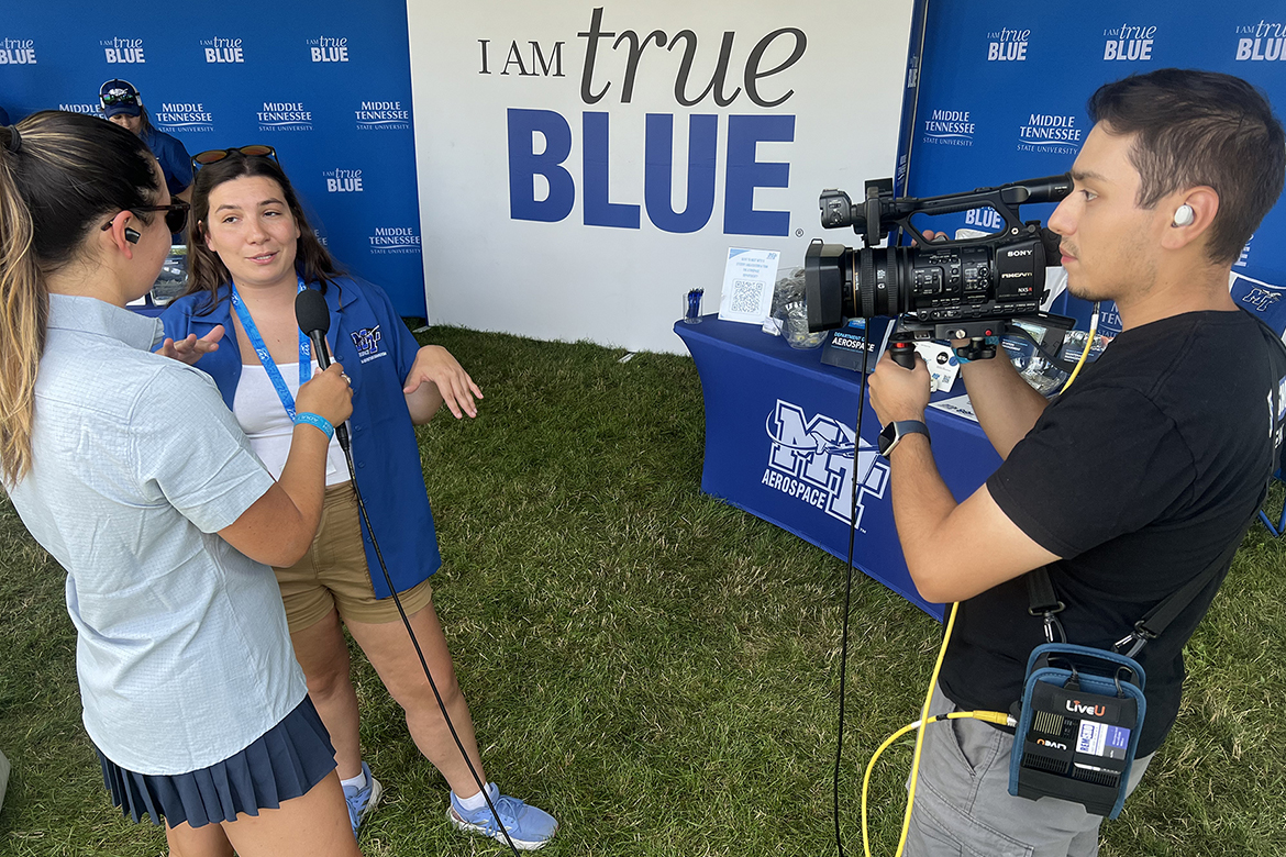 Middle Tennessee State University Aerospace Pro Pilot graduate Bri McDonald, outreach coordinator for the MTSU Aerospace Department, leads a crew from FLYING Magazine’s TV show “Oshkosh Live” on a tour of MTSU’s tent at the 2024 EAA AirVenture, held annually in Oshkosh, Wis. (MTSU photo by Andrew Oppmann)