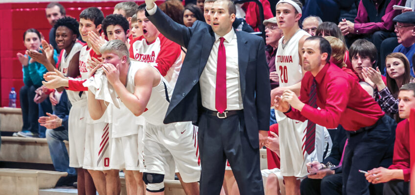 Kevin Kanaskie shoves his fist in the air as her coaches a high school basketball team. All around him, fans cheer and the team applauds.